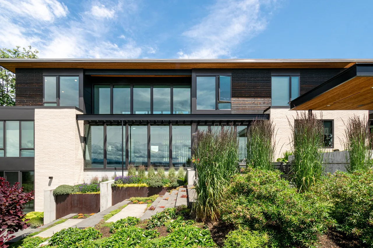 The Woodway project features a modern house with flat roof and extensive black-framed glazing overlooking a landscaped garden.