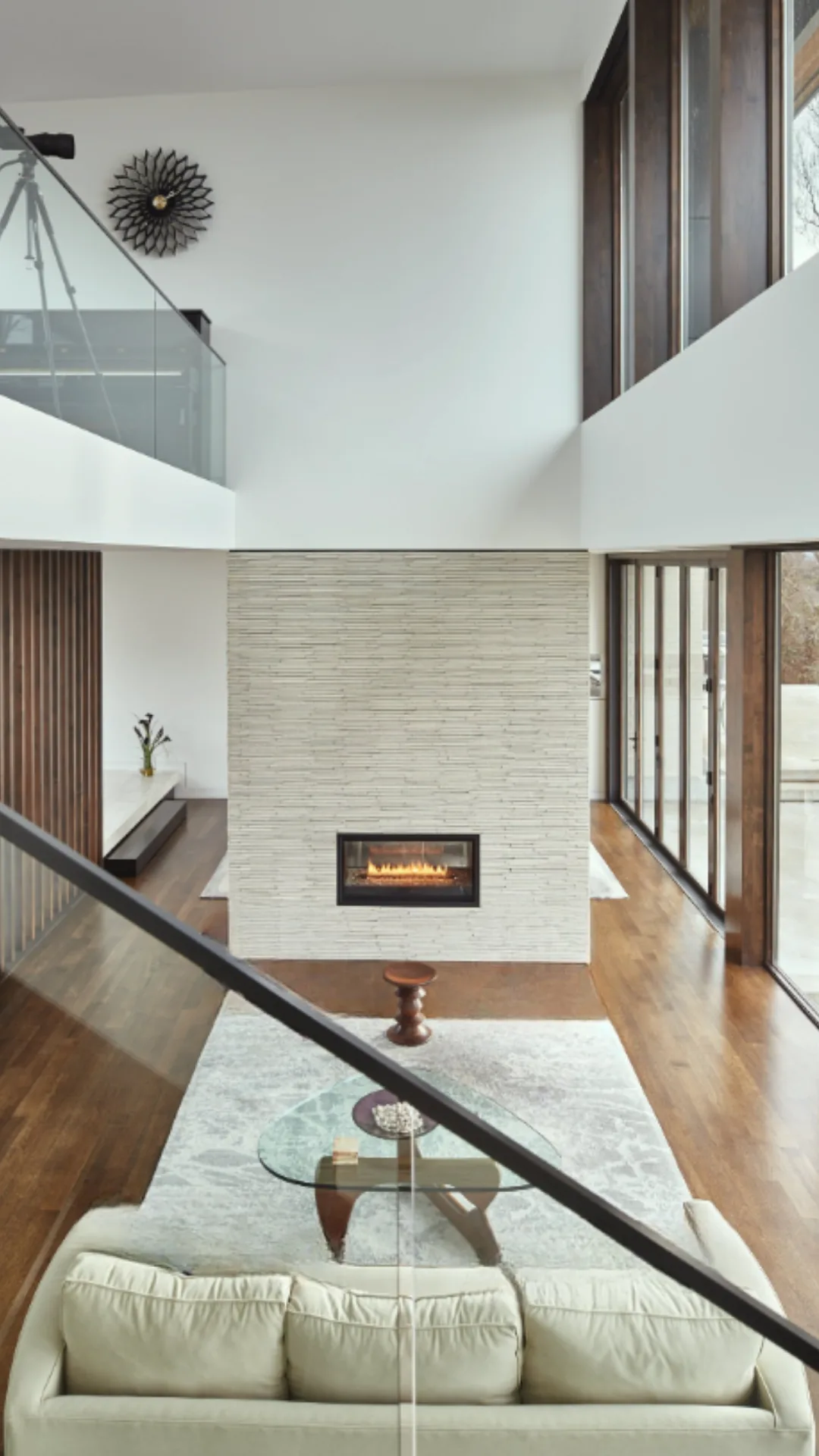 Modern living room features a built-in rectangular gas fireplace and floor-to-ceiling wood-framed windows.