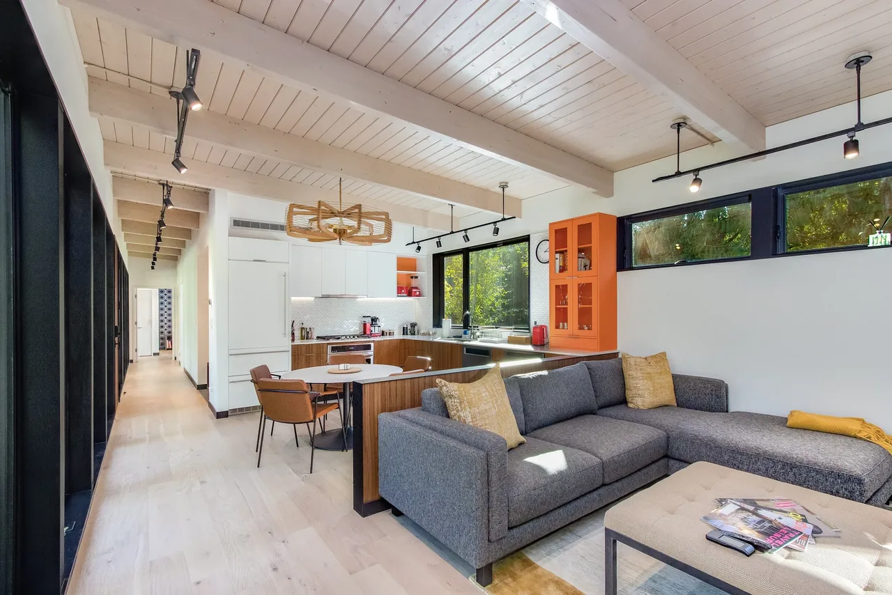 Getaway Cabin interior features an open living and kitchen space with vaulted ceiling and track lighting.