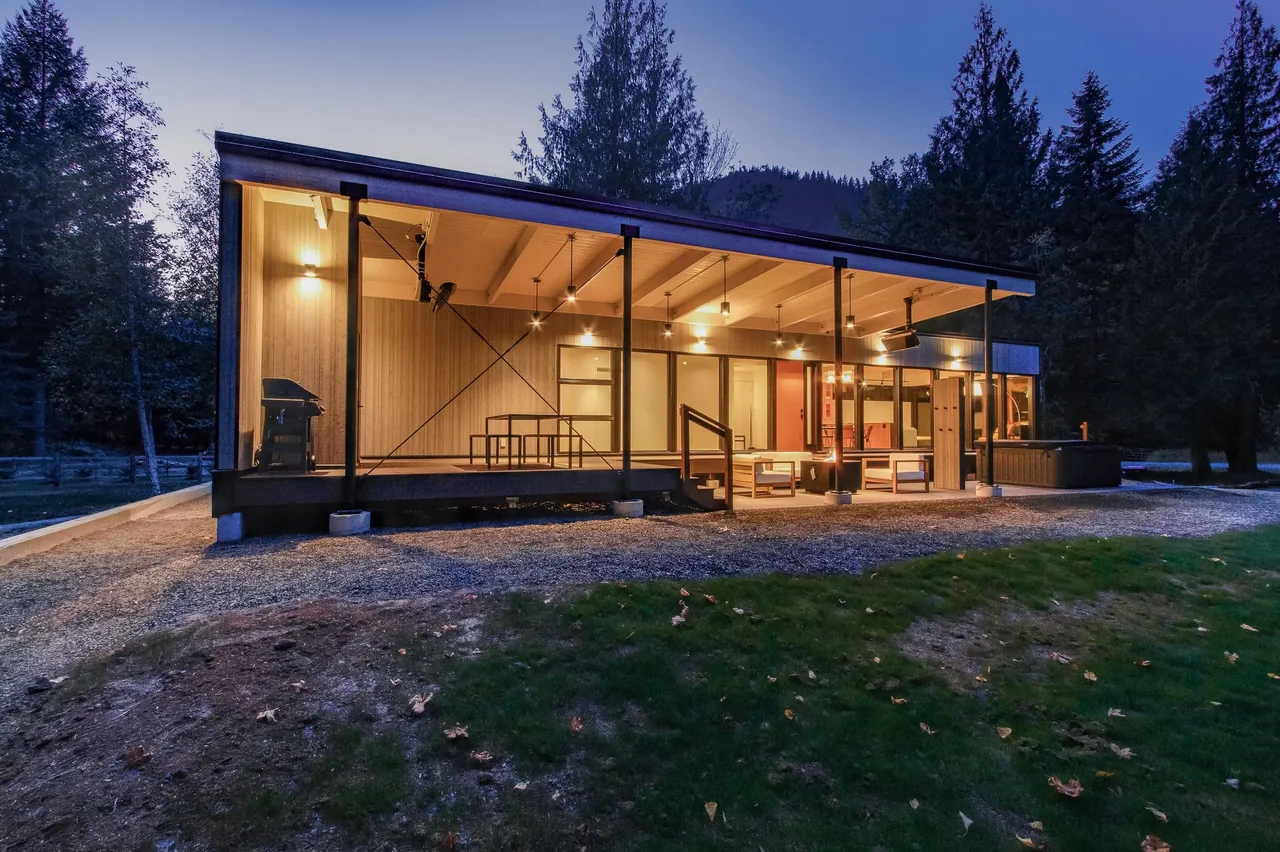 Getaway Cabin features a covered patio with wood-paneled ceiling and black steel supports, illuminated in the evening.