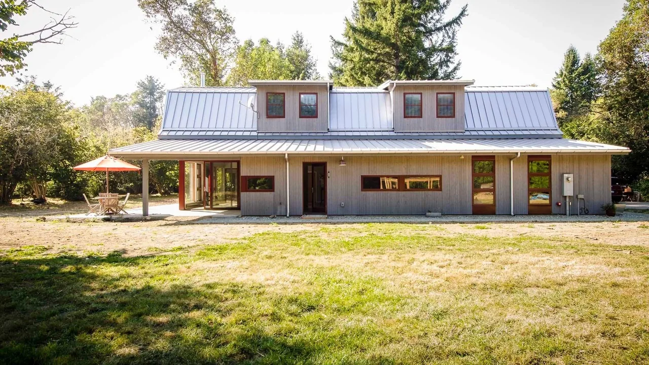 Modern house with a multi-pitched standing seam metal roof and horizontal rectangular windows under the roof dormers.