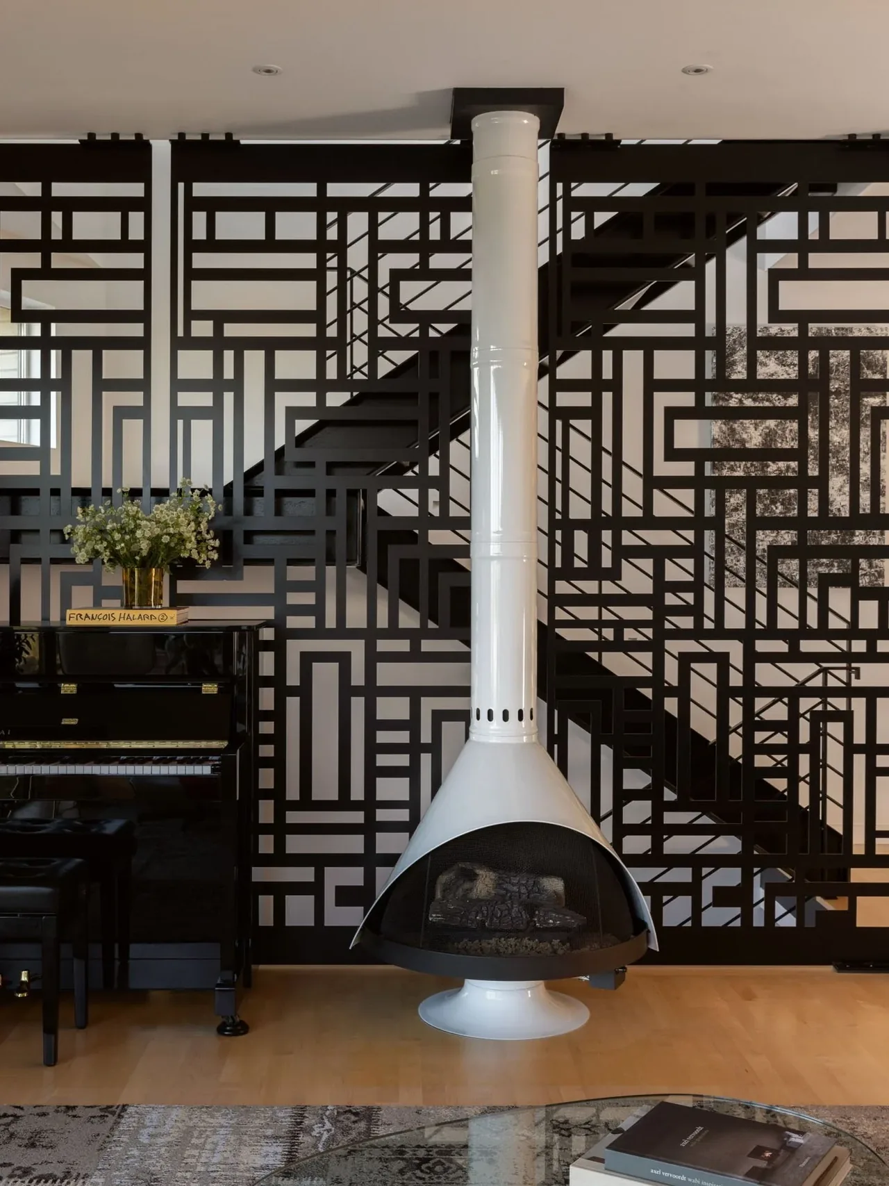Midcentury modern white fireplace contrasts with a geometric decorative metal screen and piano in a living room.