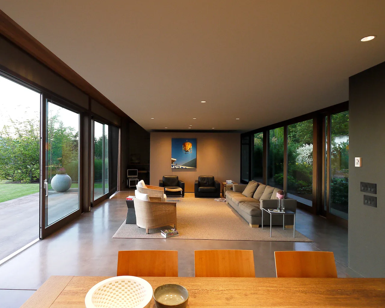 Open living room with floor-to-ceiling glass sliding doors overlooking landscaped garden and mountains.