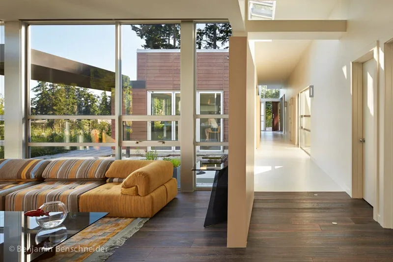 Living room area in the Island Sanctuary project with floor-to-ceiling windows and a hallway extending to the rear of the home.