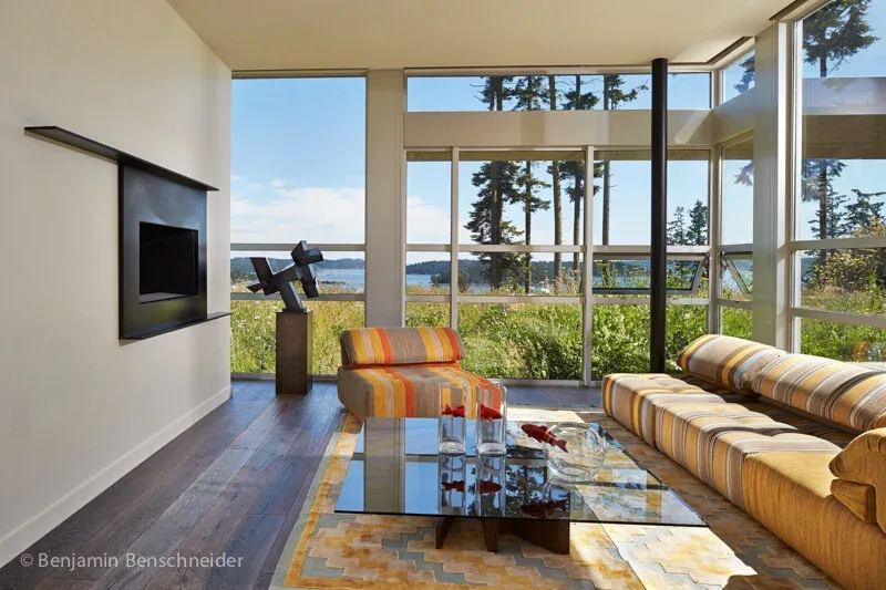 Living room in the Island Sanctuary project with floor-to-ceiling glazing overlooking natural landscaping and water views.