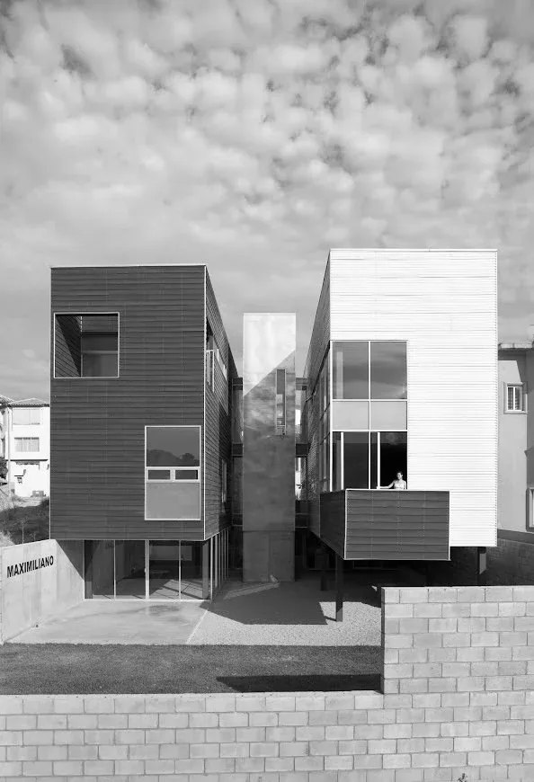 Contemporary dual-volume residence featuring contrasting dark and light facade panels and expansive windows.