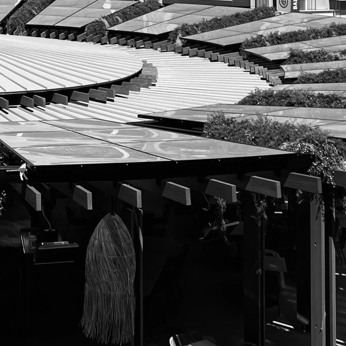Outdoor pergola with curved, horizontal wood slats and planted panels creating an integrated design.