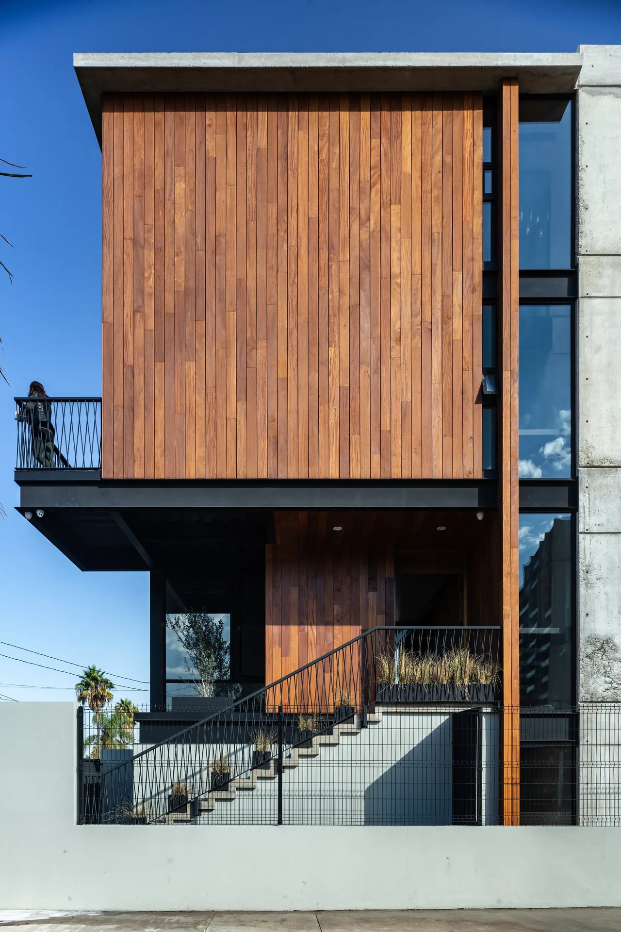 Modern house facade featuring vertical wood siding, floor-to-ceiling glazing, and concrete structural elements.