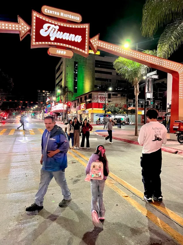 The illuminated 'Centro Histórico Tijuana 1889' sign spans the street over a lively nighttime urban scene.