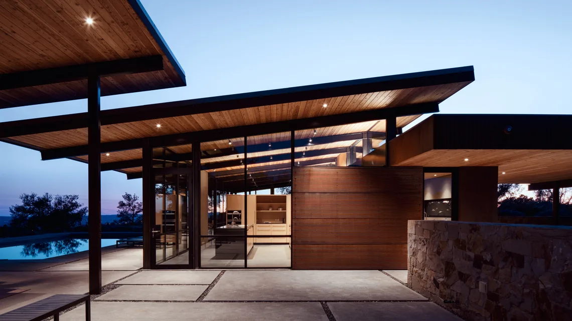 The HOUSE FOR A NEW BEGINNING by Nielsen Schuh Architects features wood-paneled ceilings and floor-to-ceiling glazing overlooking a pool area.
