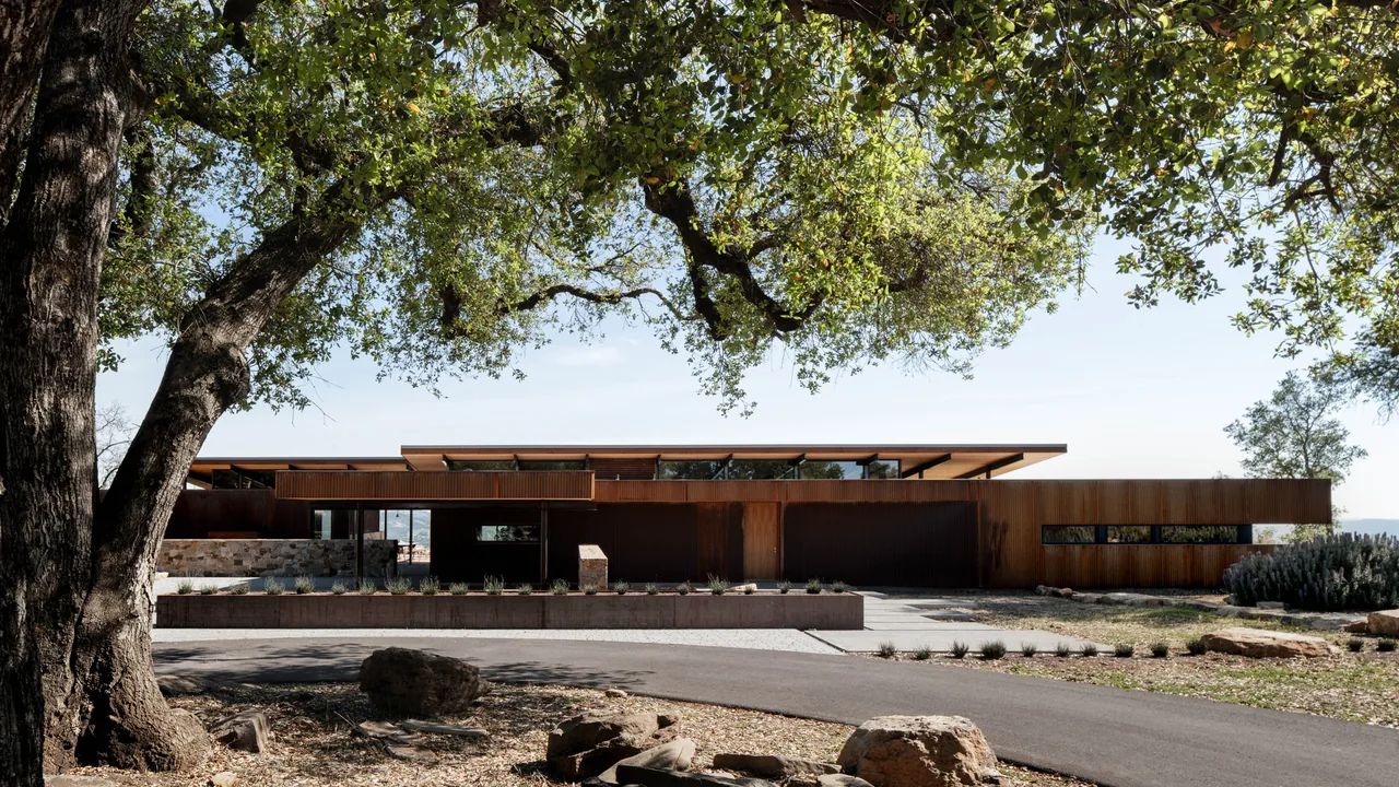 The HOUSE FOR A NEW BEGINNING features rust-colored steel cladding and a flat roof with a minimalistic design.