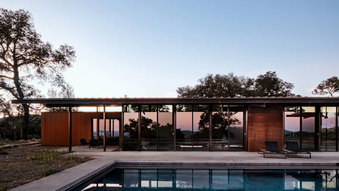 HOUSE FOR A NEW BEGINNING features floor-to-ceiling glazing and a pool with concrete deck under a flat roof.