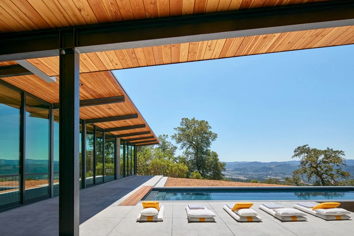 The Split Rock Springs Ranch house features floor-to-ceiling glazing and wood soffits with views over a mountainous landscape.