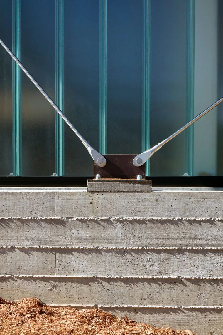 Detail of concrete base with corrugated frosted glass panel supported by metal tension rods at Split Rock Springs Ranch.