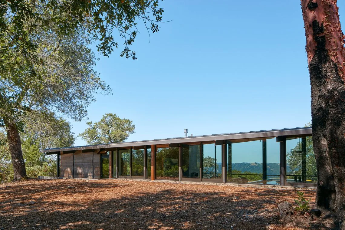 Split Rock Springs Ranch house featuring a flat roof and expansive floor-to-ceiling glazing overlooking natural surroundings.