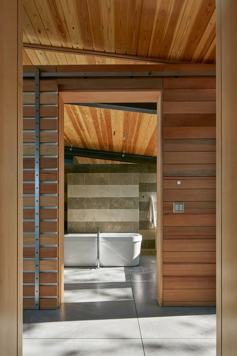 Bathroom features a freestanding tub against a striped stone tile wall beneath a wood-paneled ceiling at Split Rock Springs Ranch.