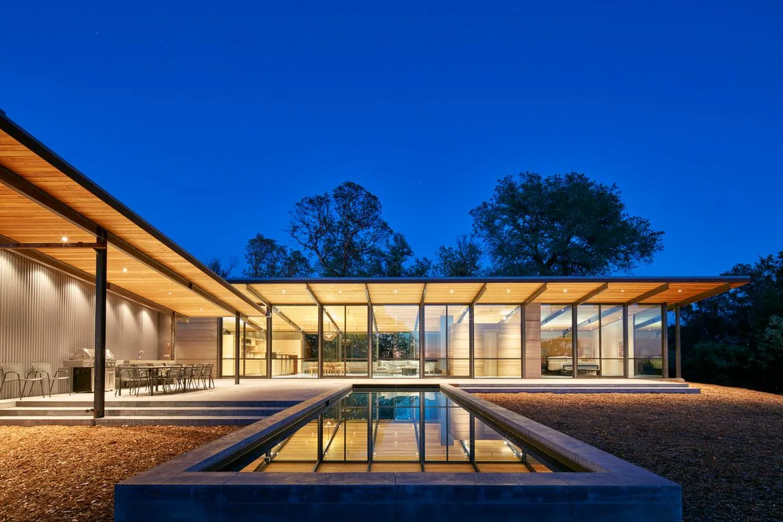 The Split Rock Springs Ranch features glass walls, a sloping wood ceiling, and a reflecting pool by Nielsen Schuh Architects.