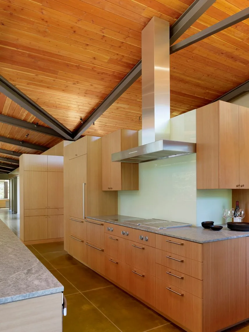 Kitchen featuring wood cabinets, stainless steel range hood, and a wood ceiling with black steel beams.