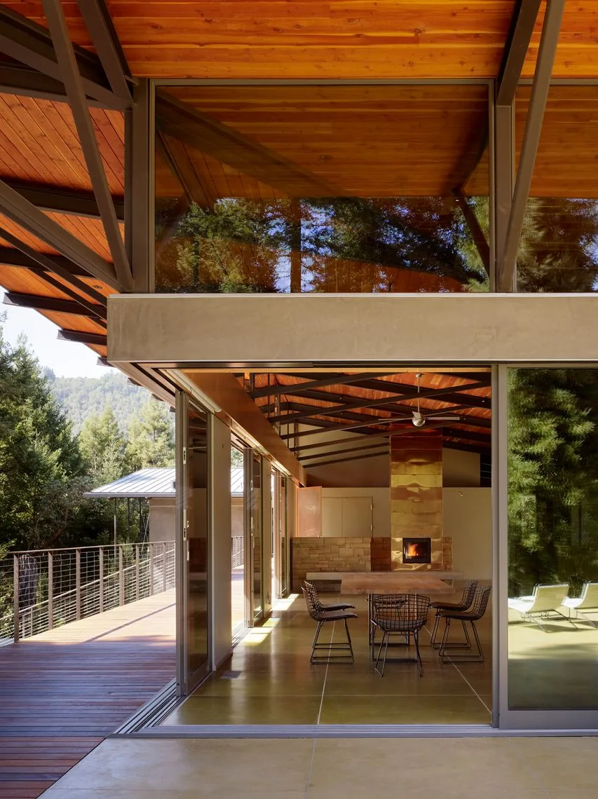 Sonoma Mountain House dining area with copper fireplace and wood-paneled ceiling extends to a raised foundation deck.