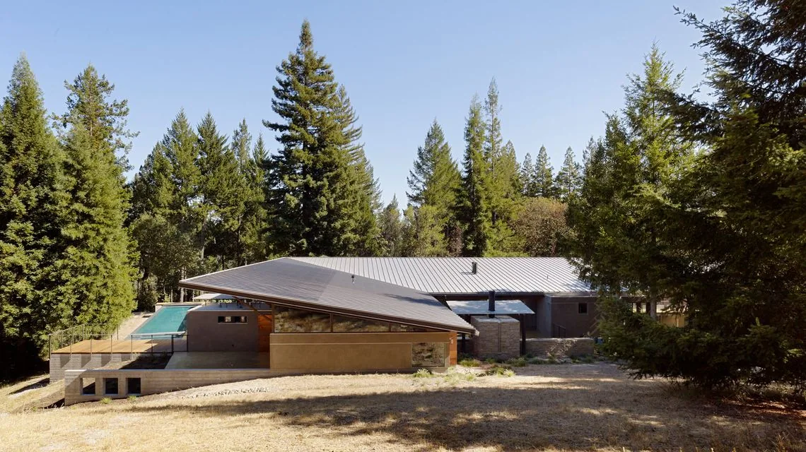 Sonoma Mountain House features a sloped standing seam metal roof and raised foundation surrounded by forest.