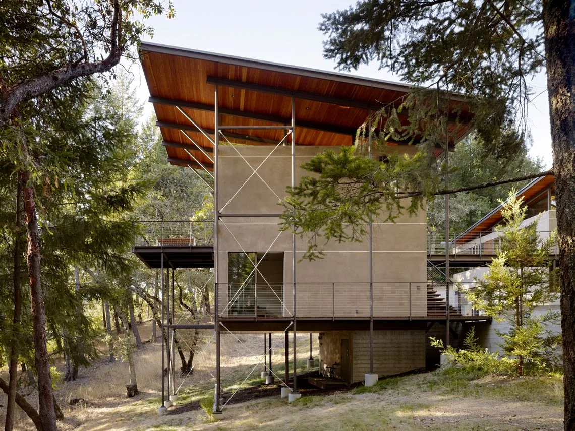 Sonoma Mountain House features a raised foundation with a tall, overhanging flat roof in a forest setting.