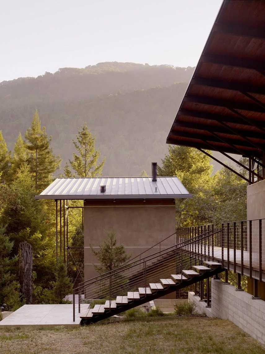 Sonoma Mountain House features a raised concrete foundation and metal railing stairs connecting to a wood-paneled upper deck.