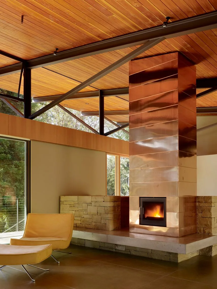 Copper fireplace in a modern living room with wood ceiling and large glazing walls at Sonoma Mountain House.