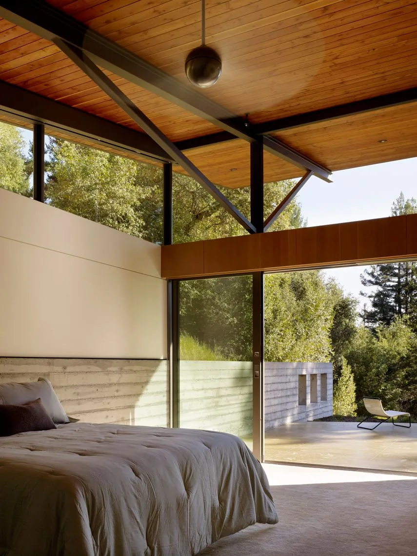 Bedroom in the Sonoma Mountain House with floor-to-ceiling sliding glass doors and a wood-paneled ceiling.
