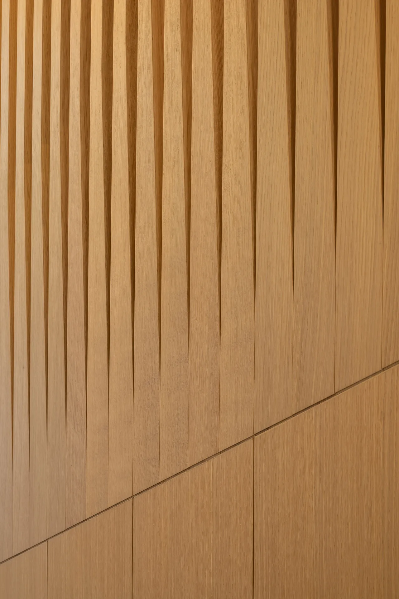 Wood wall detail featuring vertical slats with a contrasting smooth wood panel below.