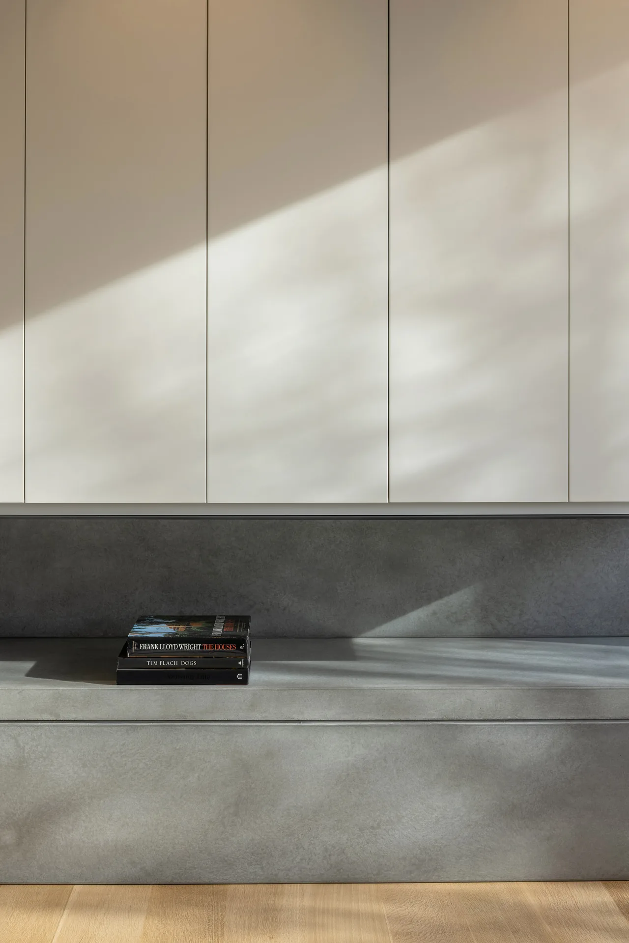 Modern kitchen cabinetry features white upper panels and gray concrete lower cabinets with a few books on the counter.