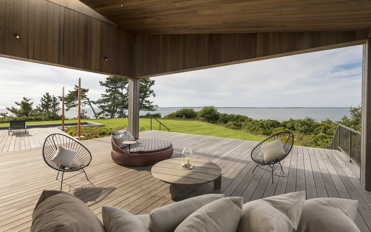 Outdoor living space with wood deck and ceiling looking out to a waterfront landscape.