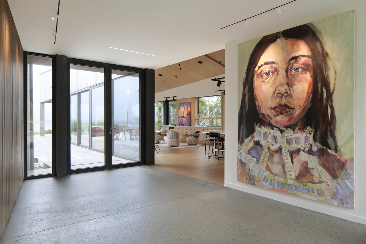 Entry hallway with polished concrete flooring, black window frames, and large portrait artwork near living space.