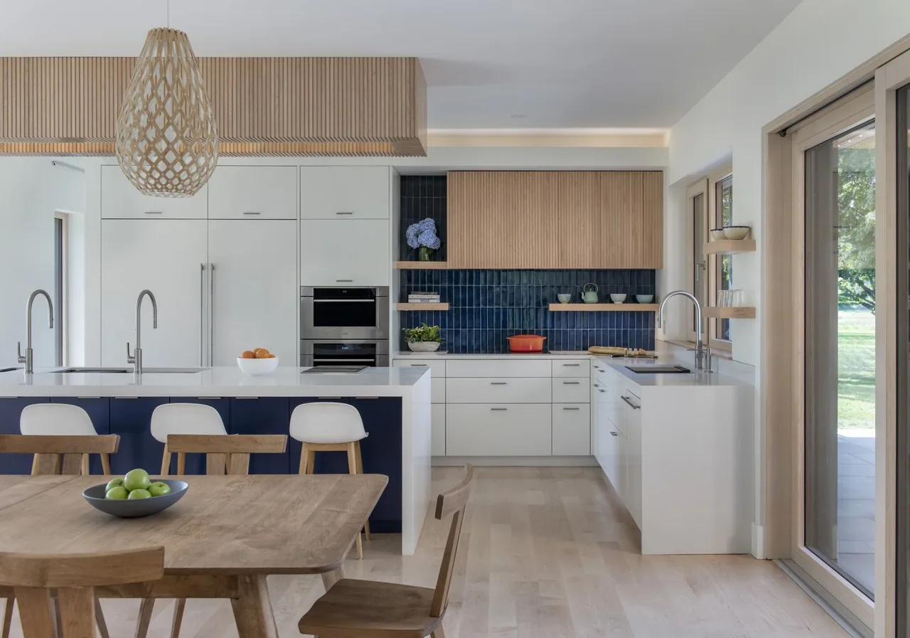The kitchen features white cabinetry, wood upper cabinets, blue tile backsplash, and a kitchen island with seating.