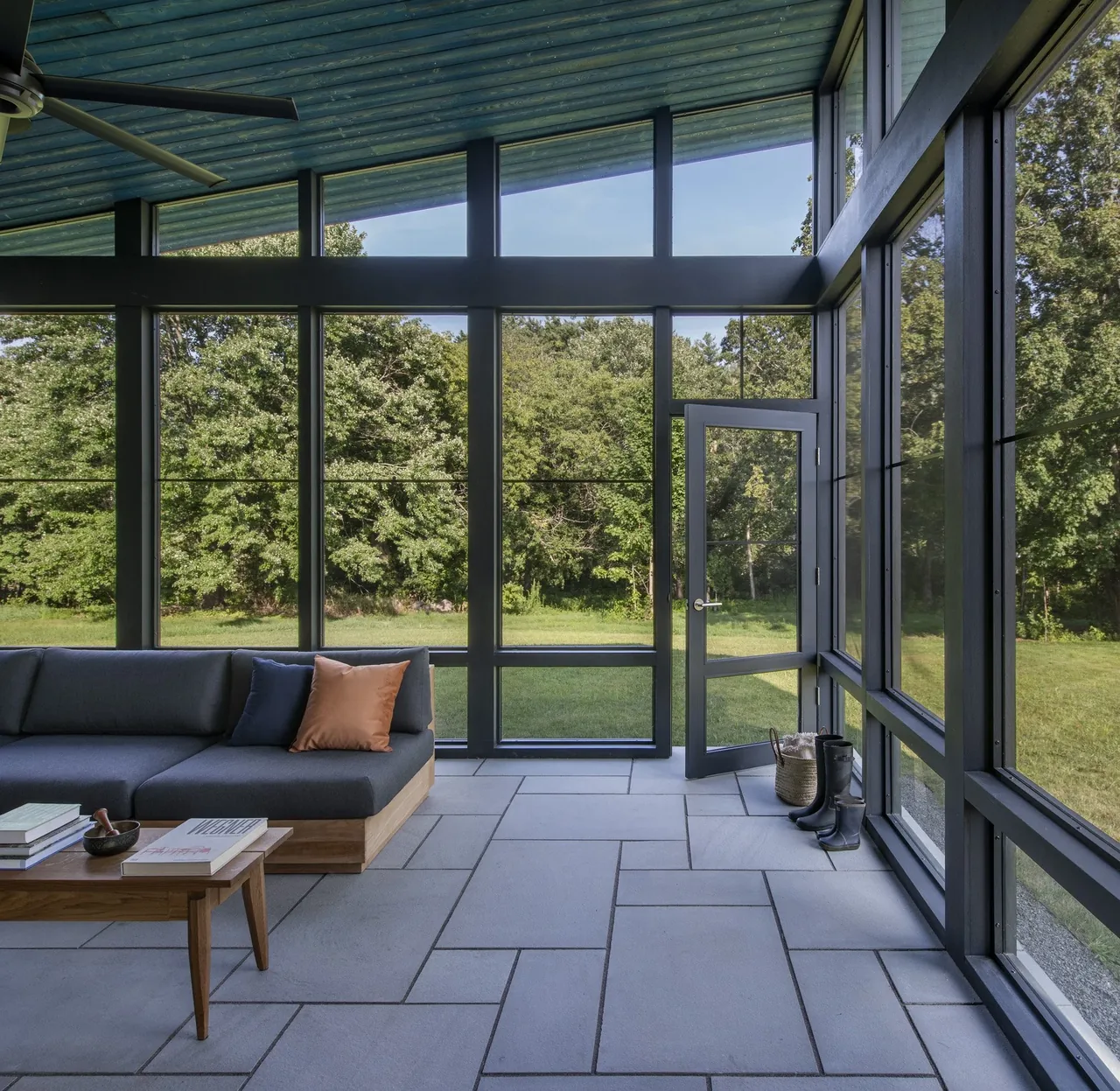 Screened porch with floor-to-ceiling glazing and a wooden coffee table in Stow Passive House.