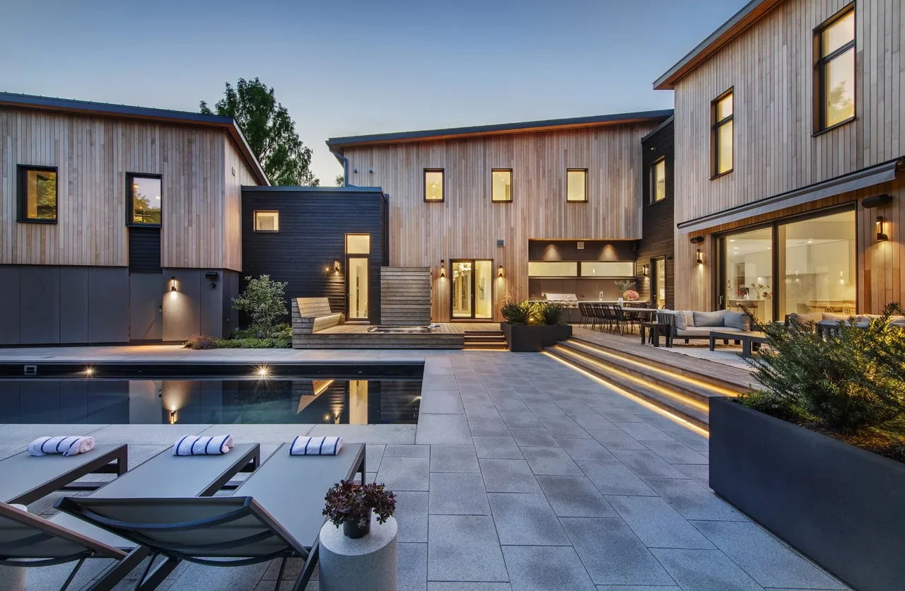 Backyard of Belmont Modern 2.0 featuring a pool, lit multi-level steps, and large vertical windows at dusk.