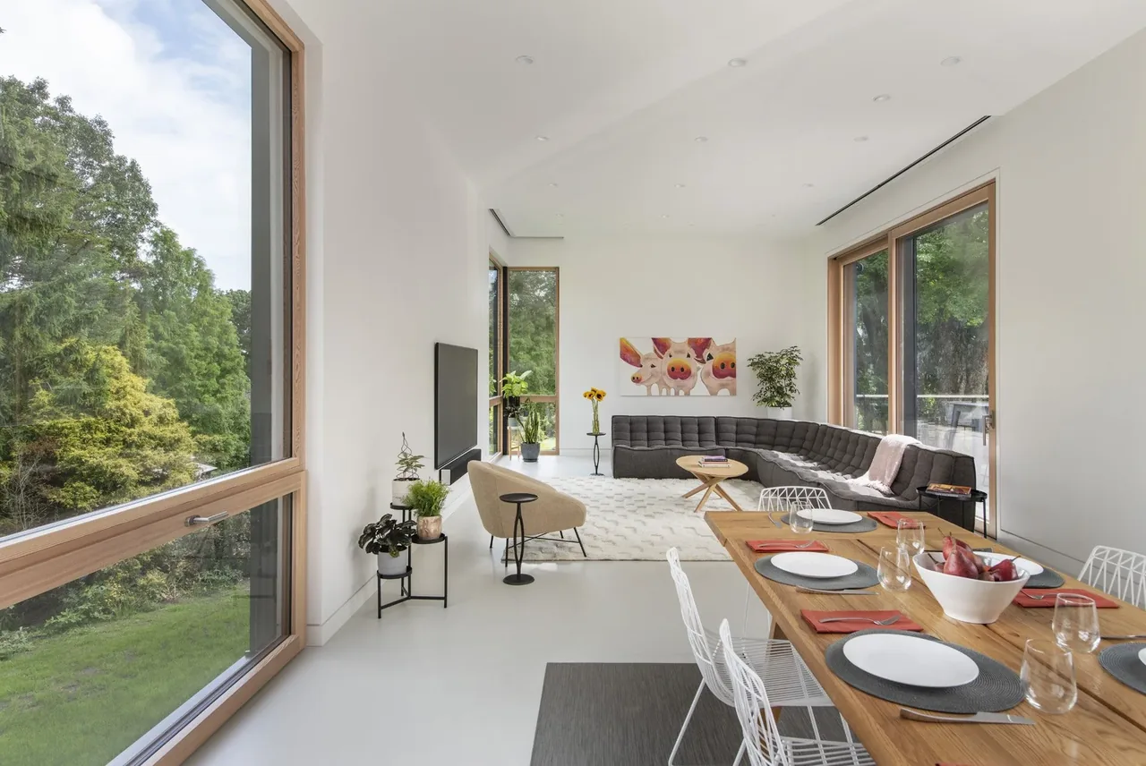 Belmont Modern 2.0 features a spacious living and dining area with extensive wood window framing and minimalist furniture.