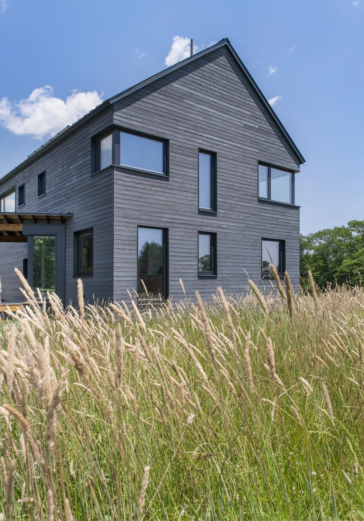 Westport Modern Home features horizontal wood siding and corner windows with black frames in a rural setting.