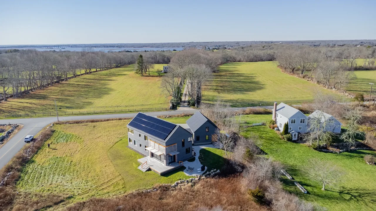 Westport Modern Home by ZeroEnergy Design features solar panels and a stone wall, set in a rural landscape near Boston.