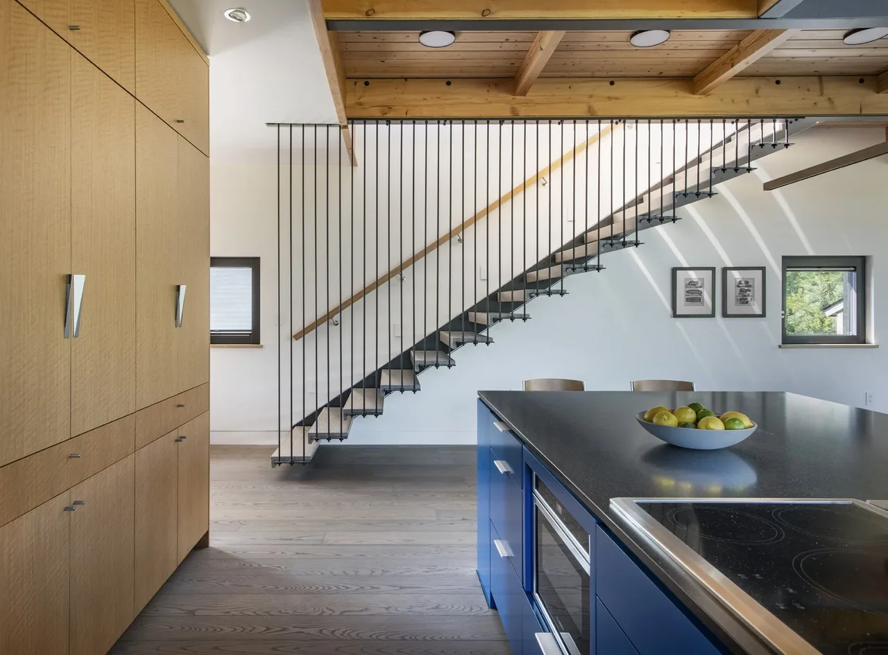 Kitchen and stair area in the Westport Modern Home featuring a blue island and minimalist stair design.
