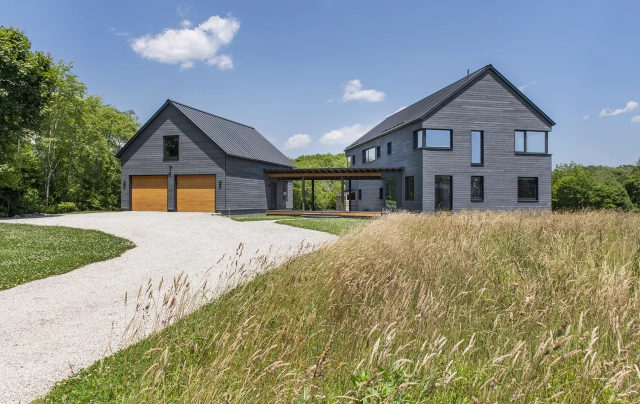 Westport Modern Home features two gray gable-roofed structures connected by a pergola breezeway in a rural field landscape.