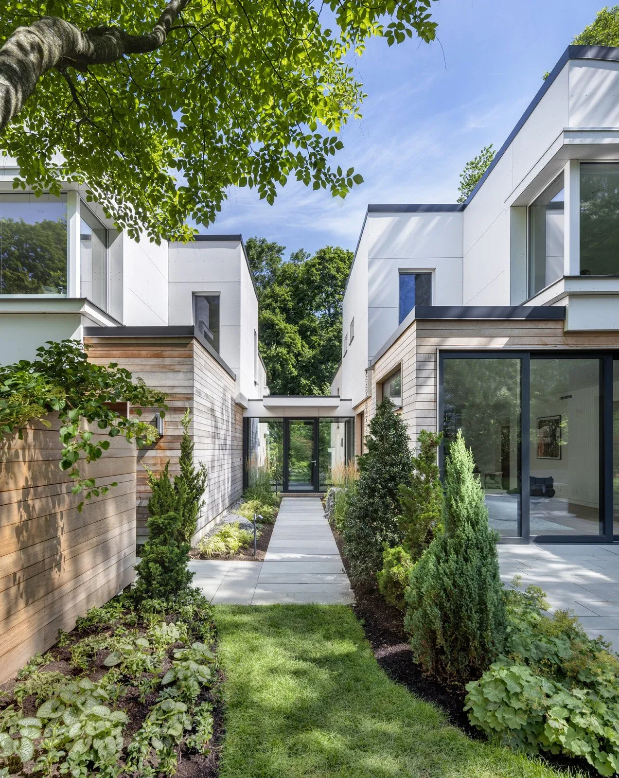 Belmont Modern features a two-story white and wood exterior with landscaping and a paved walkway between structures.