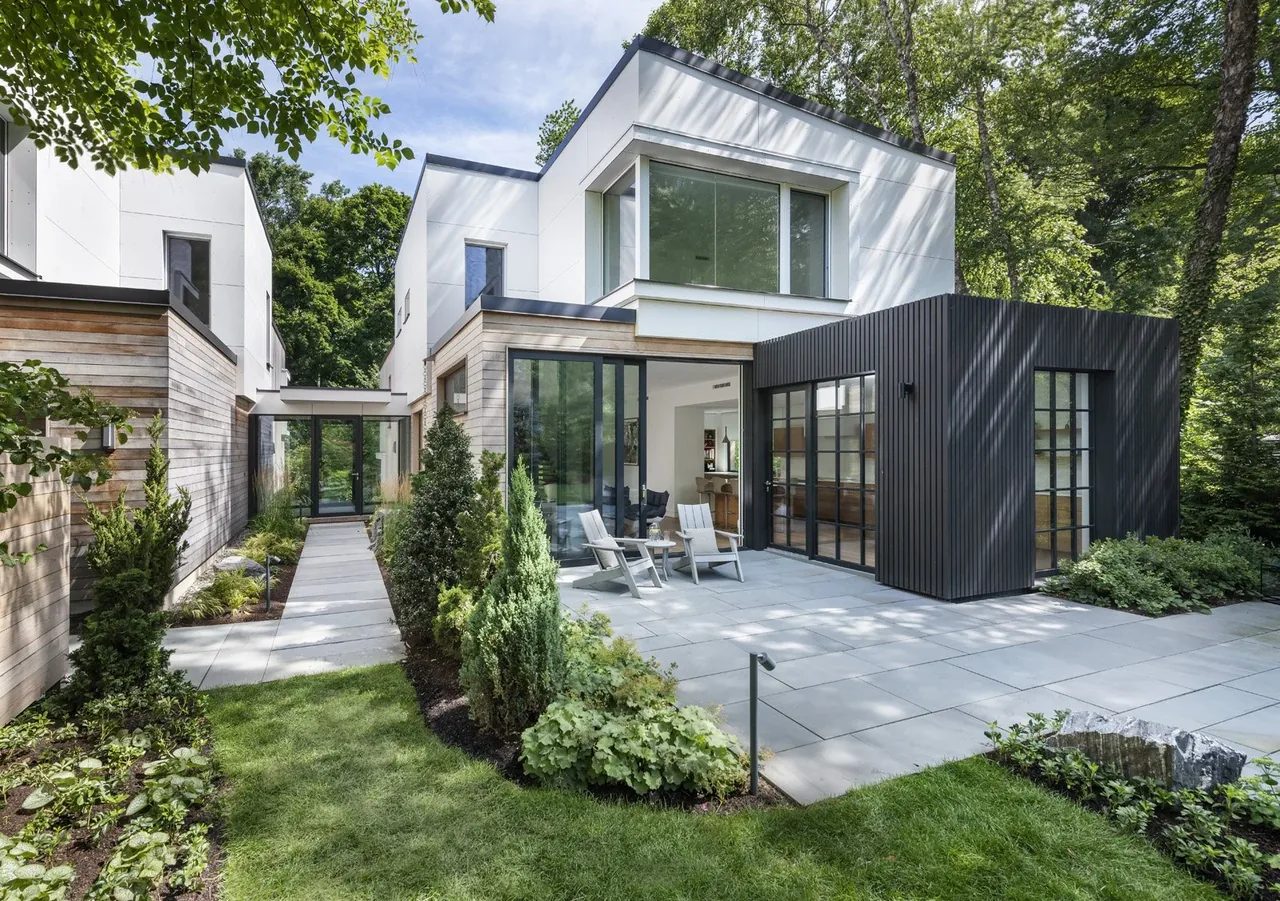 The Belmont Modern home features a landscaped yard, patio with seating, and floor-to-ceiling glazing for natural light.
