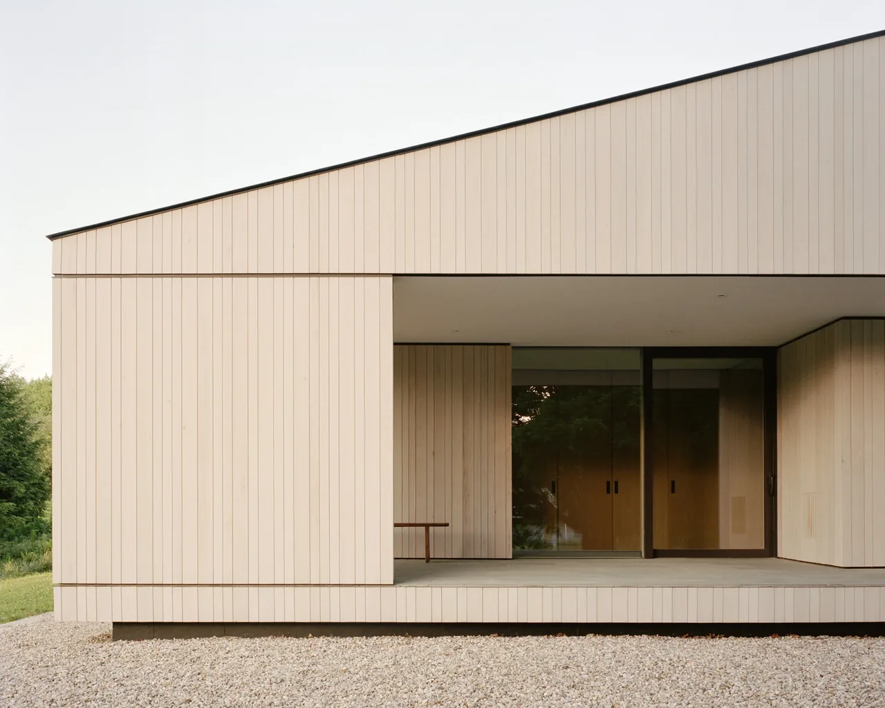 The Berkshire Residence features vertical wood siding and a covered outdoor patio with glass sliding doors.