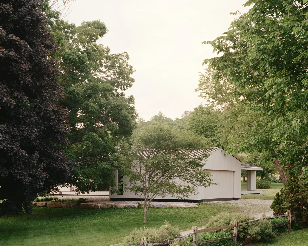 Berkshire Residence features a white wood-sided exterior with a gable roof, set in a landscaped green environment.