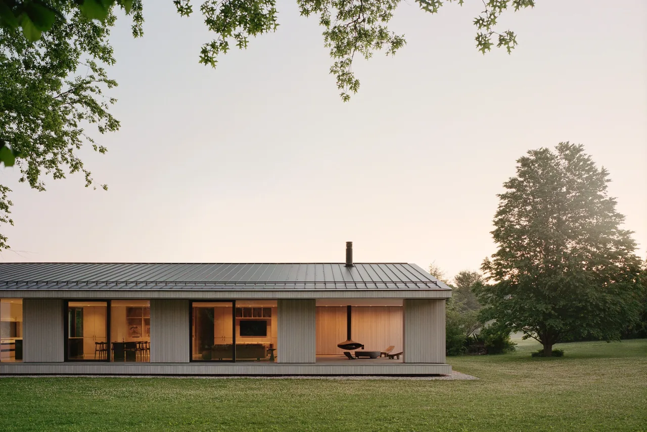 Berkshire Residence features vertical wood siding, floor-to-ceiling glazing, and a standing seam metal roof in a rural setting.