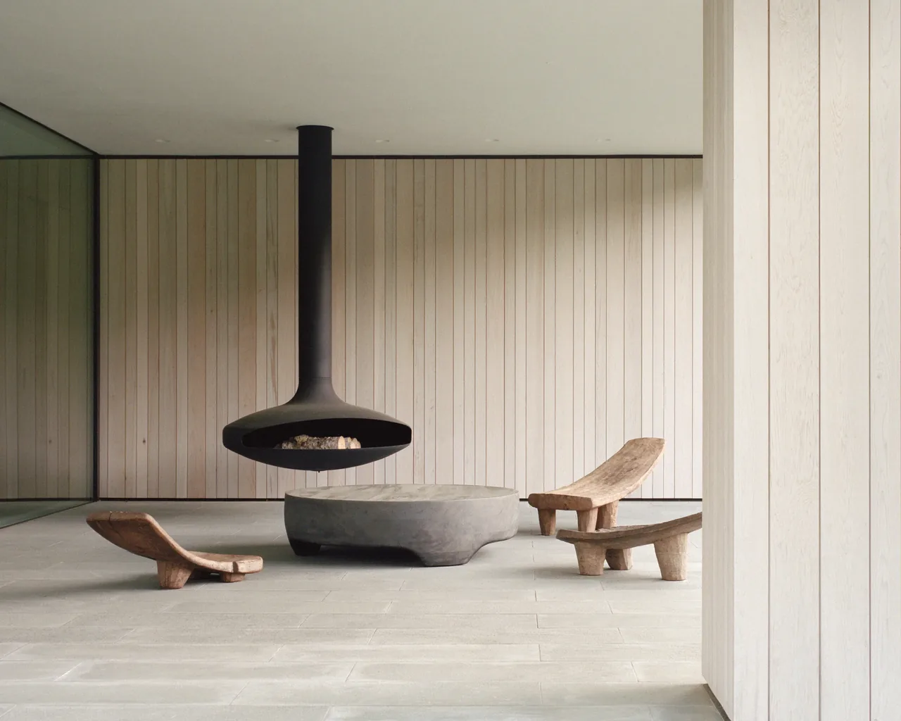 The Berkshire Residence features a covered patio with a floating black fireplace and natural wood seating.