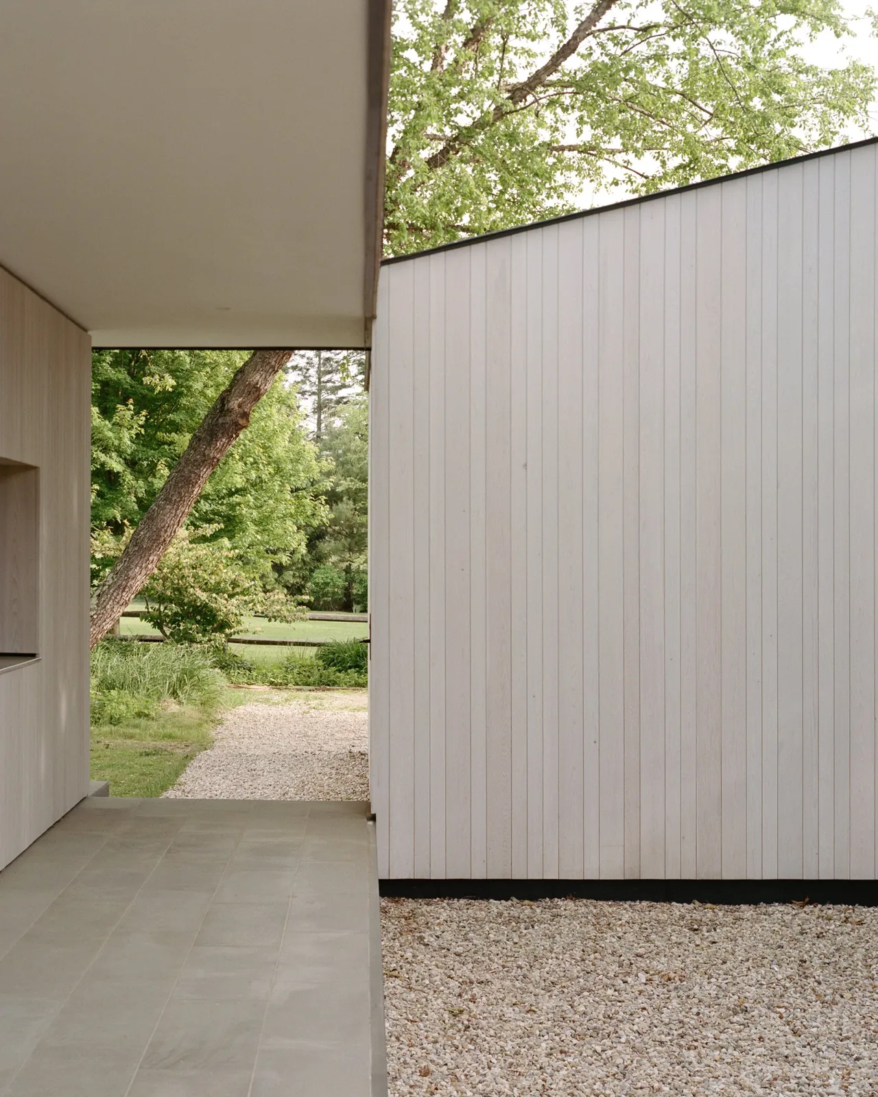 Covered pathway with vertical wood siding and gravel landscaping at Berkshire Residence.