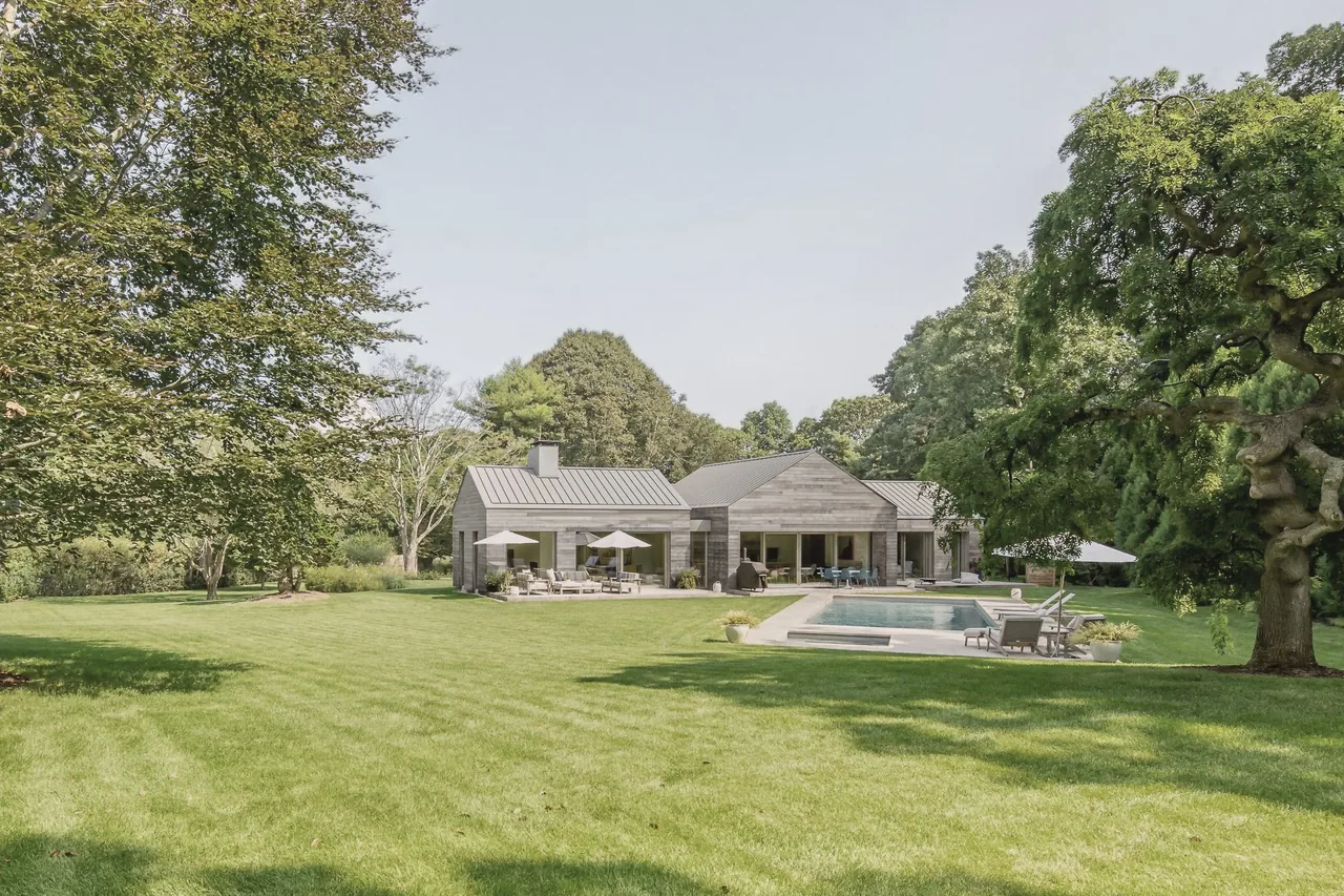 East Hampton Residence features metal roofing and horizontal siding with a pool and patio area.