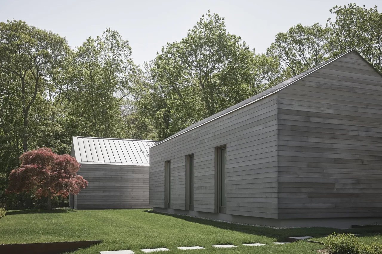 East Hampton Residence features horizontal wood siding and metal gable roofs on adjacent building wings.