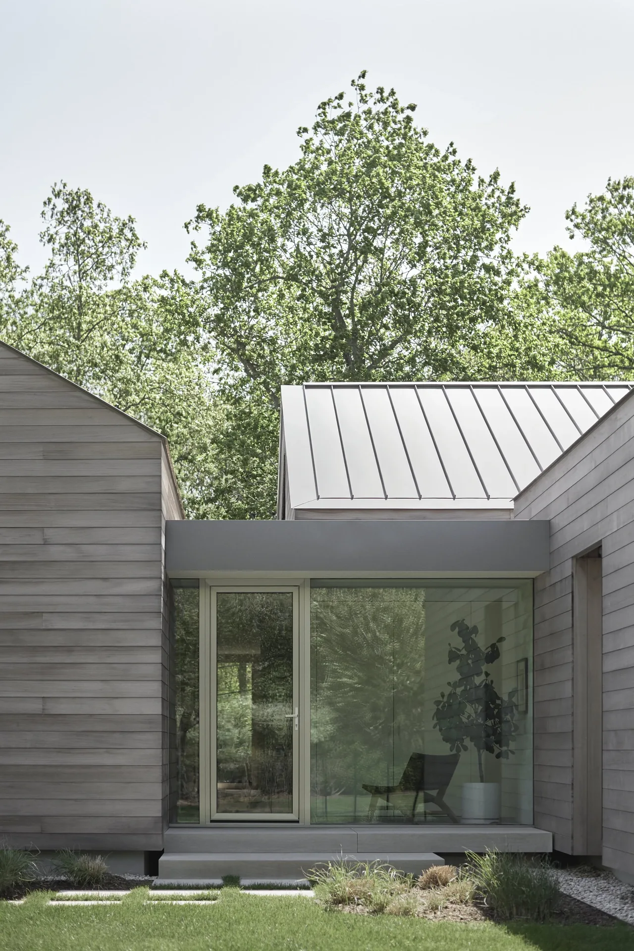 Modern residence entrance with horizontal wood siding and a standing seam metal roof section.